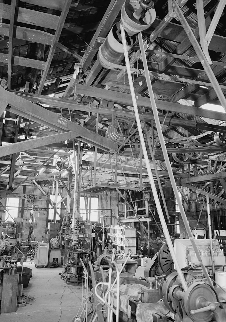 Early 20th century machine shop showing a line shaft with leather belt drives connecting industrial machinery